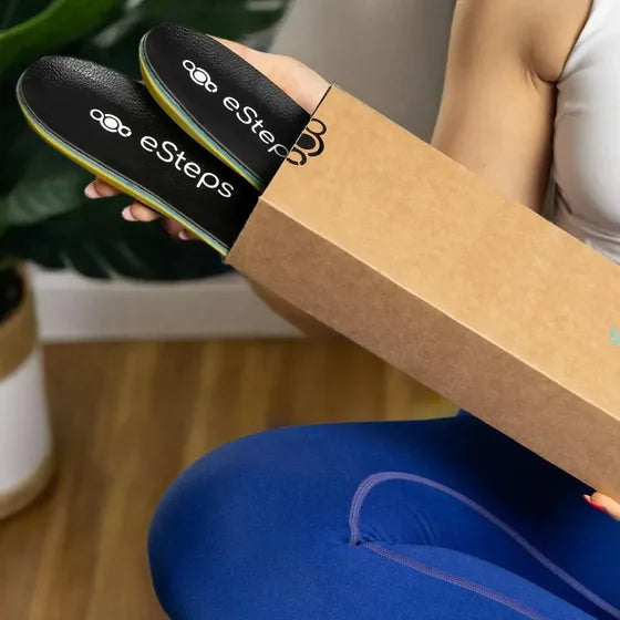 The eSteps insoles held at the mouth of their kraft box.