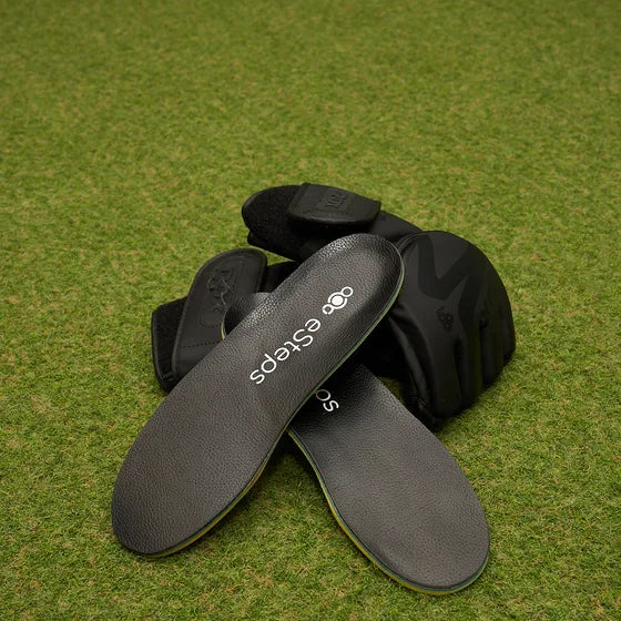 The eSteps insoles resting on grass beside a pair of gloves.