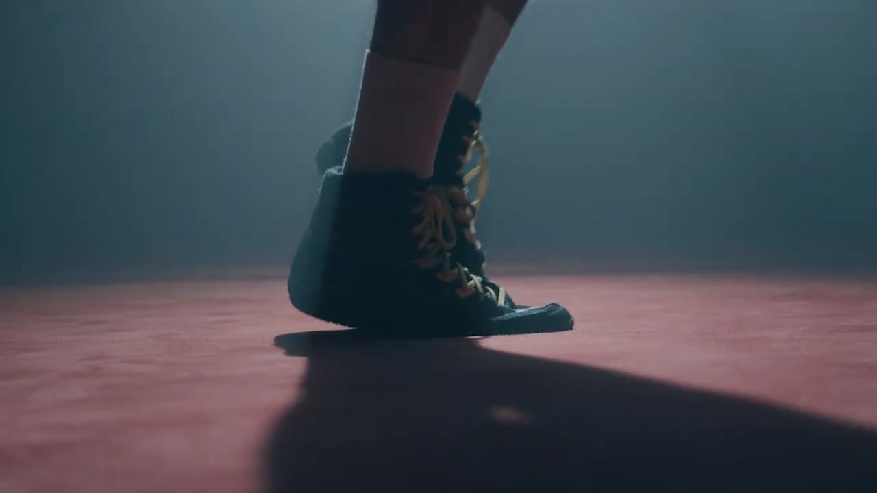 A person in laced trainers mid-step on a studio floor