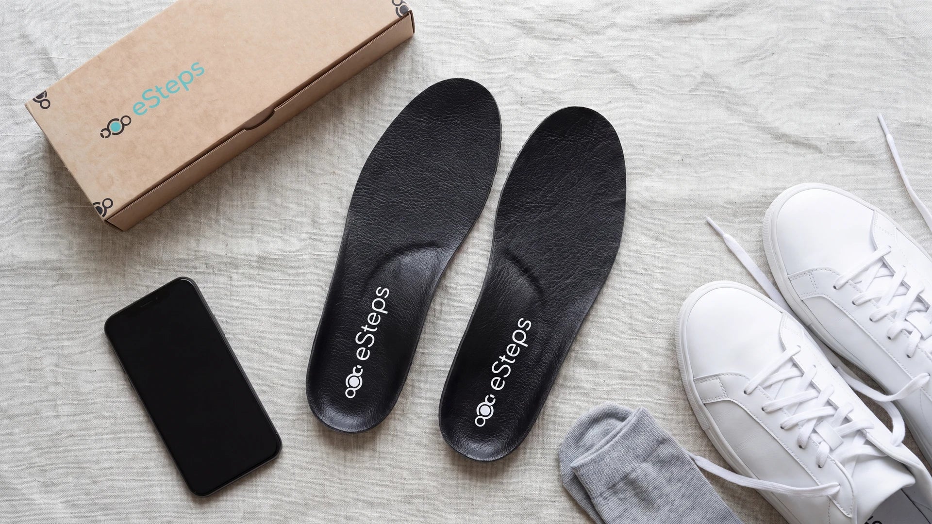 The eSteps insoles laid out beside the box they arrive in and a phone running the app.