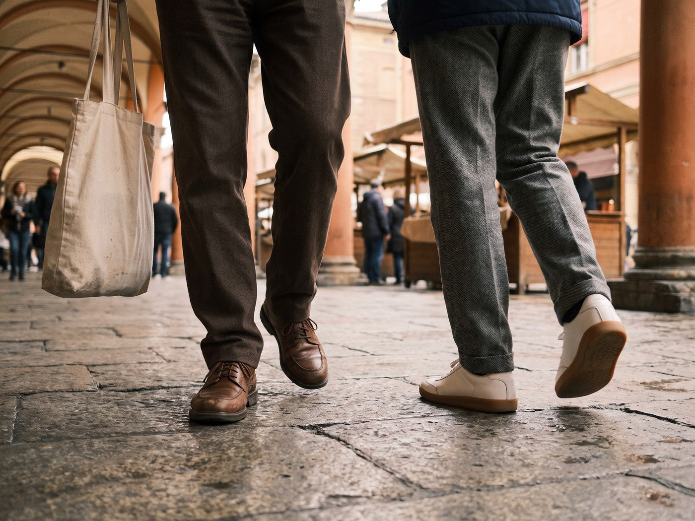 Two people walking along a street, seen from the knees down